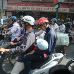 Armador av skotrar och motorcyklar präglar många storstäder. Baby matas med nappflaska under färd i Saigon, Vietnam.