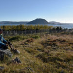 Precis här uppfördes bosättningar av de nordbor som för tusen år sedan koloniserade vad de kallade Västerbygden, på sydligaste Grönland. Här är relativt frodigt, Efa Poulsen på bilden är trädgårdsmästare vid den lantbruksskola som döljer sig bakom träddungen.